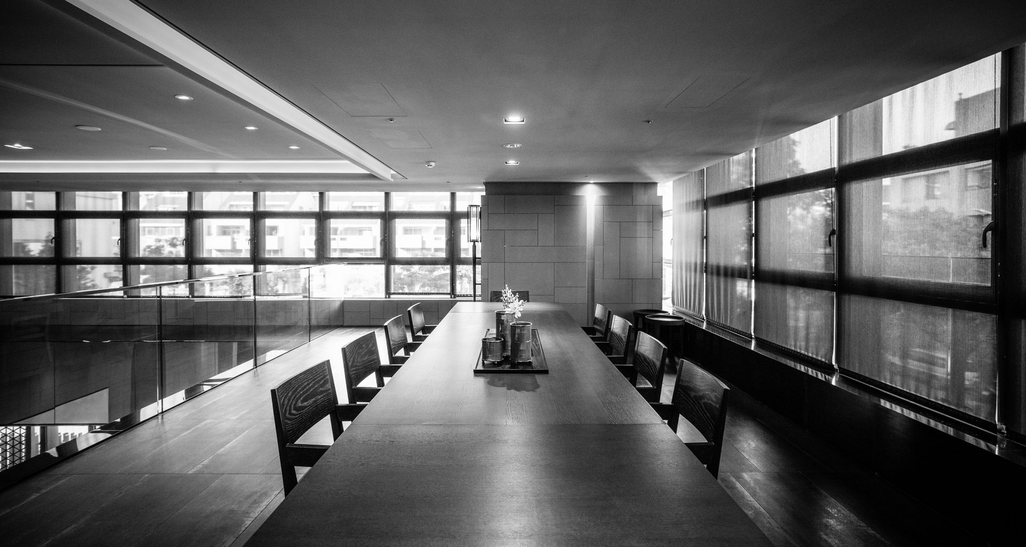 A long boardroom table in soft black and white light